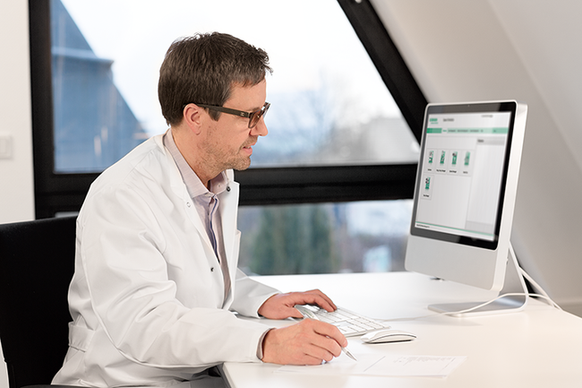 Trained personnel sitting at computer preparing medication with help of software.