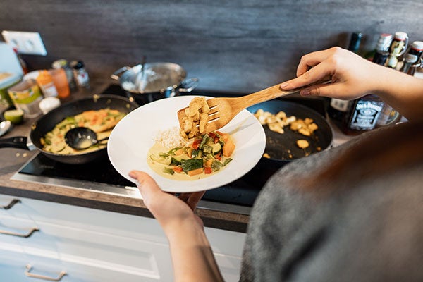 Gesundes und stomagerechtes Essen wird von einer Frau auf einen Teller gelegt. 