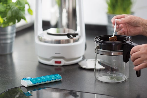 Eine Patientin füllt Kaffeepulver in ihre Kaffeemaschine.