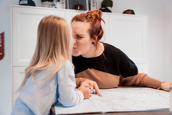 Eine junge Frau kuschelt mit ihrem Kind im Grundschulalter. 