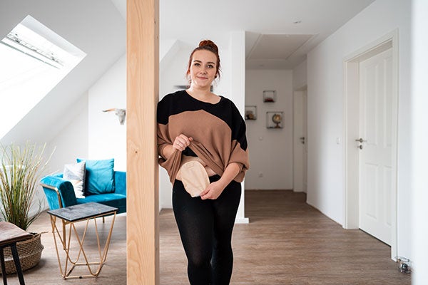 Eine junge Frau zieht ihr Oberteil etwas hoch, um ihr Stoma zu zeigen. 